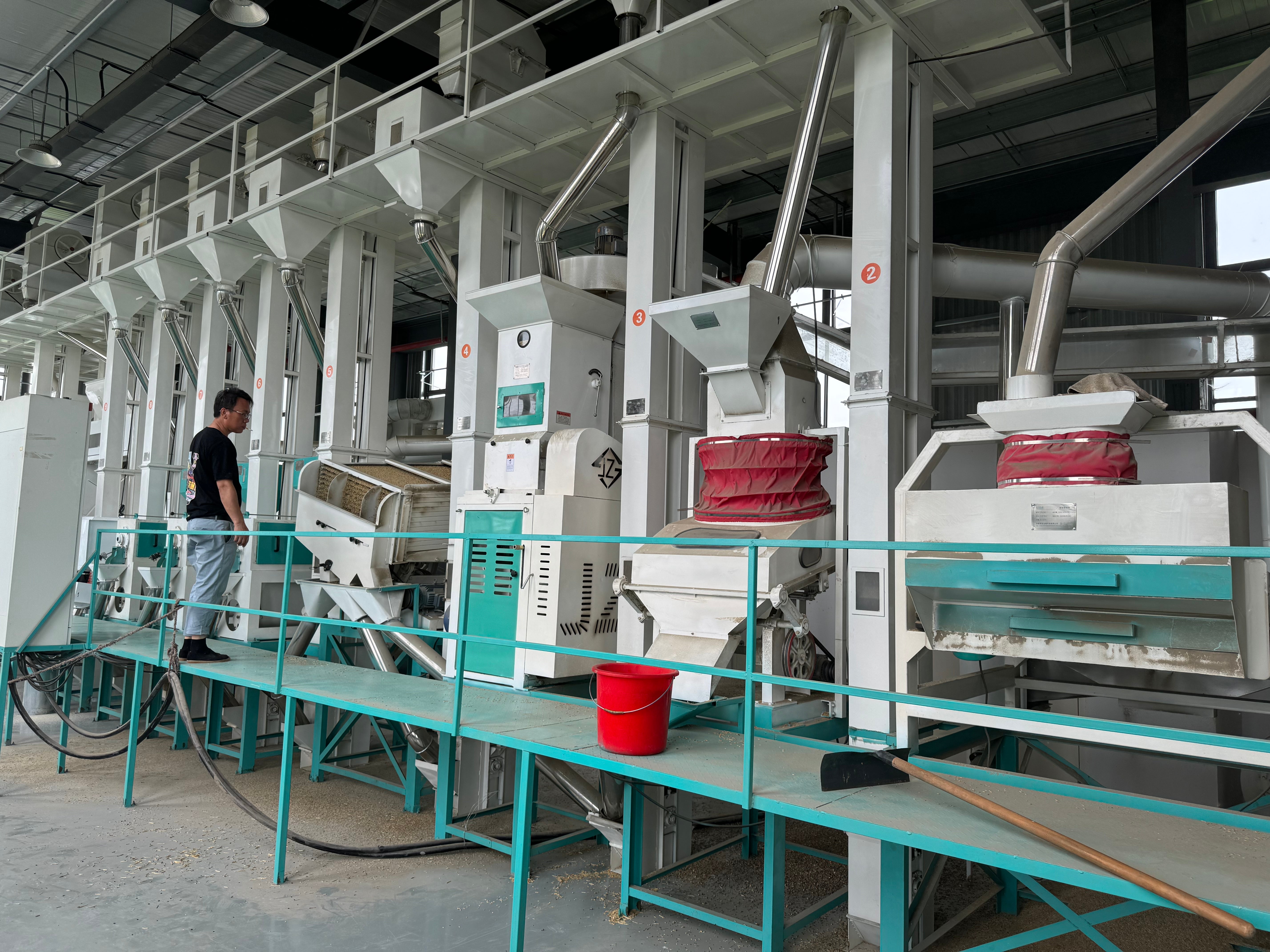 Industrial rice processing plant with machinery and a worker.