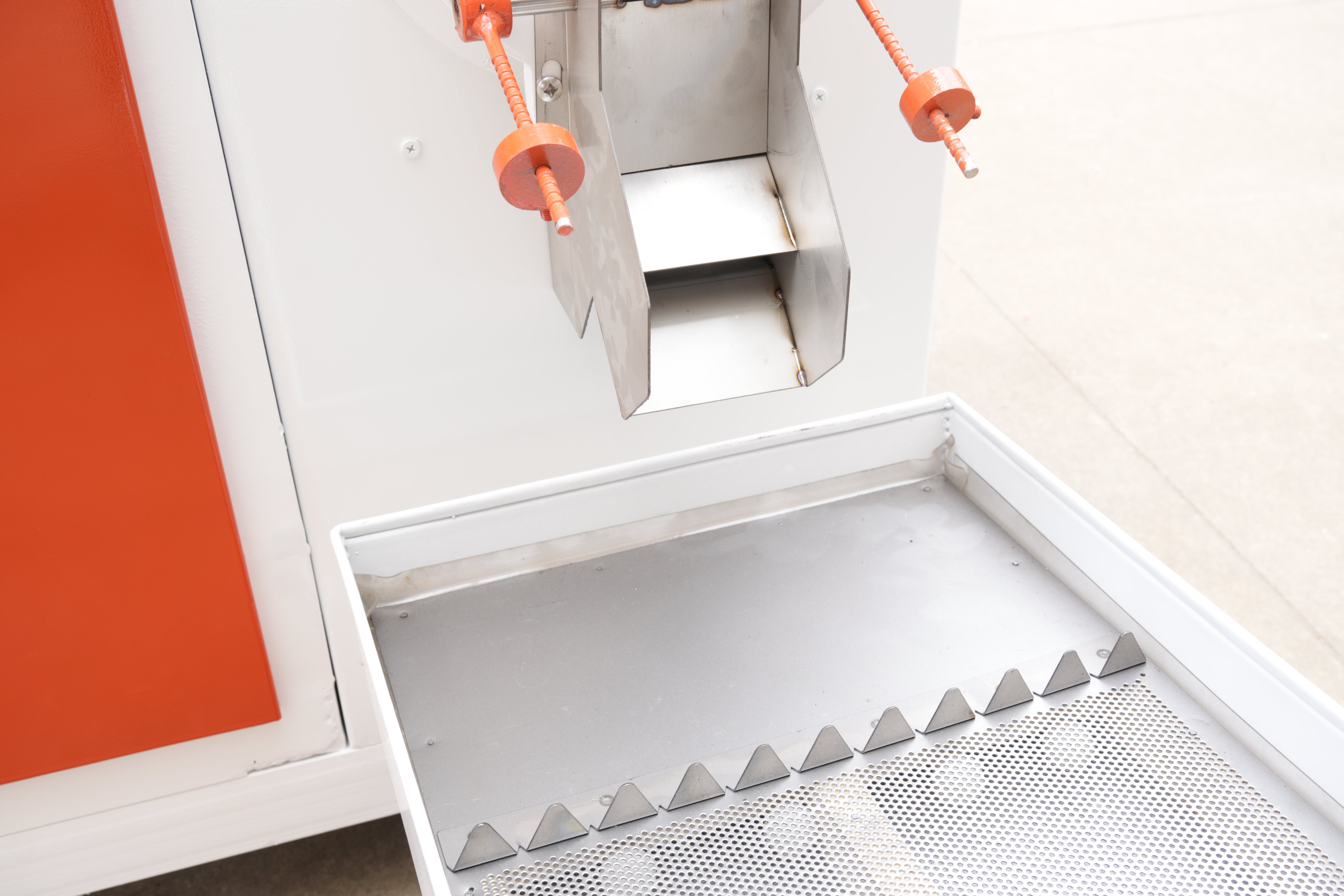 Metallic staircase with orange handrails against a white wall.