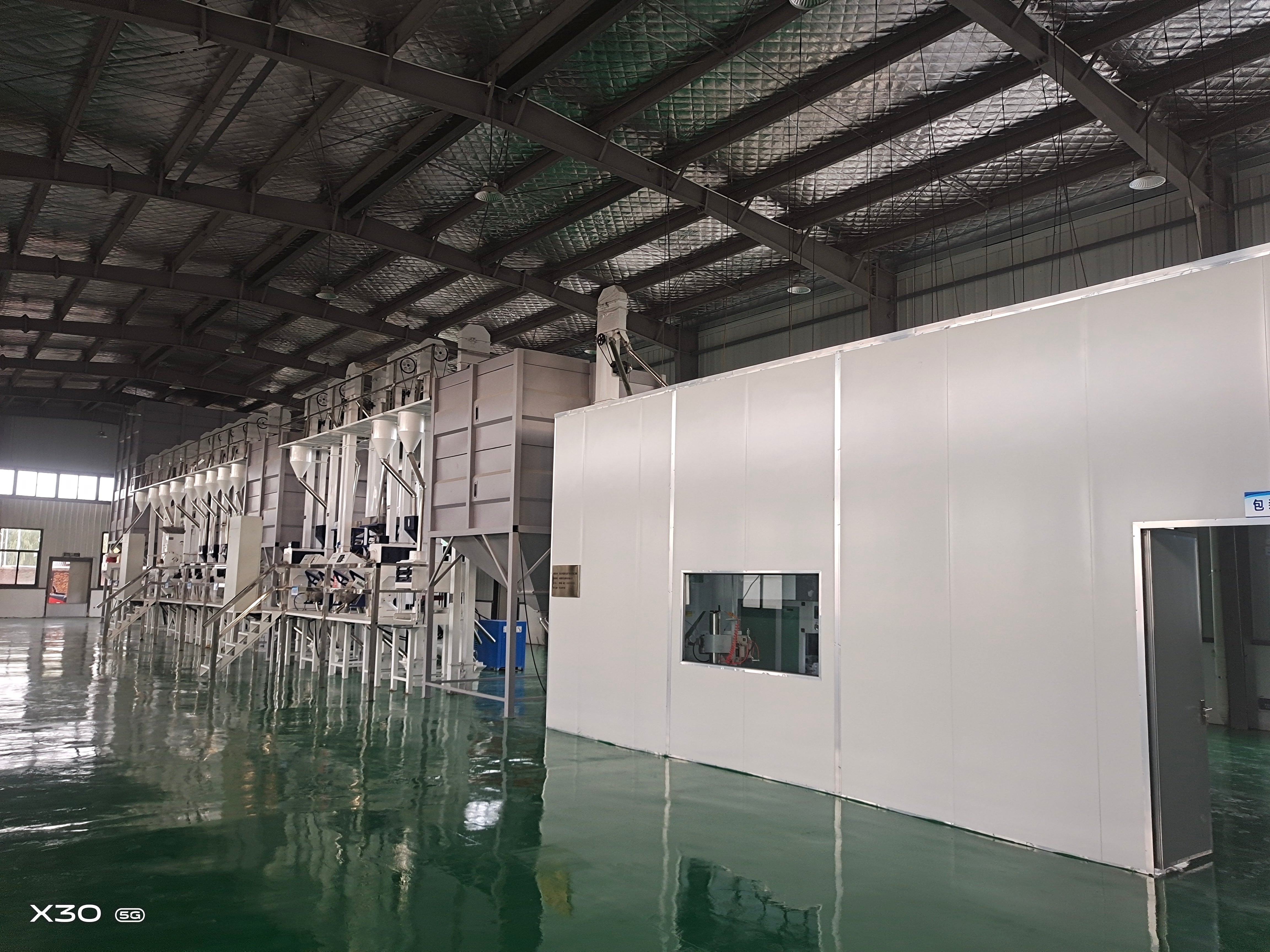 Large industrial building with white walls and metal beams on a reflective floor.