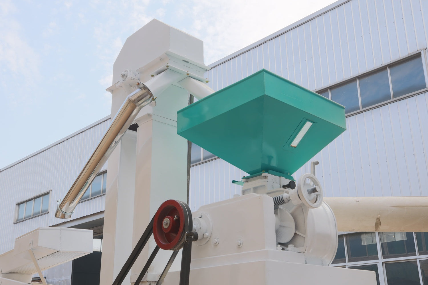 Industrial machine with a green hopper in front of a building
